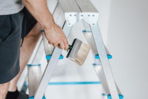 person painting on stepladder